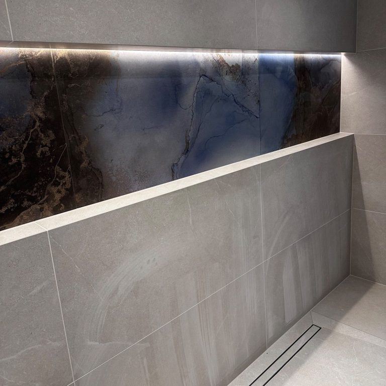 Moderne Badezimmerwand mit dunklem Marmor und sanfter LED-Beleuchtung.